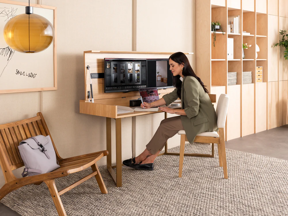A tidy desk arranged with a raised monitor, supportive chair and a glass of water